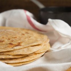 An upclose shot of a stack of paratha in a white kitchen towel