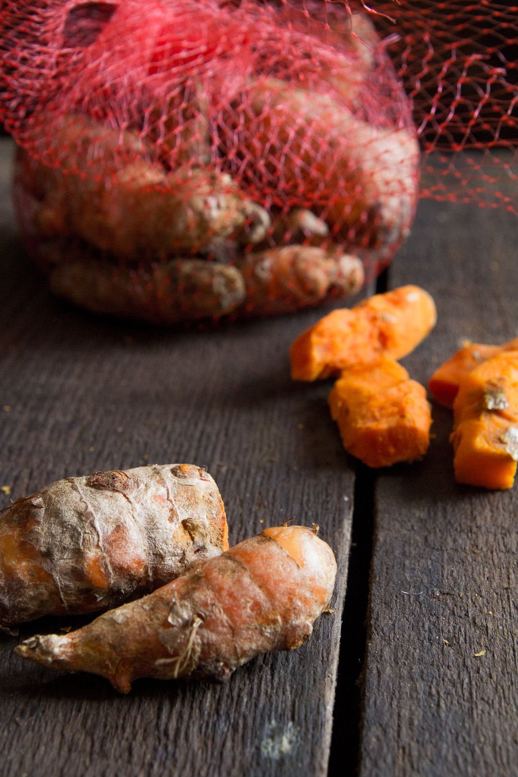 Fresh turmeric laid out in front of a bag. Some of it is freshly peeled.