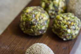 Date bites with pistachios, poppy seeds and almond coating on a piece of dark wood