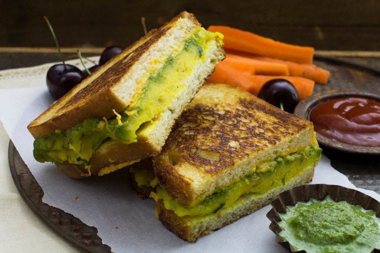 masala cheese toast sandwich cut into half with carrots, cherries, ketchup and chutney on white paper