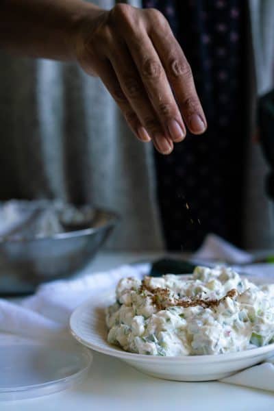 Sprinkling toasted and ground cumin seeds on the raita