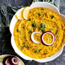 square top shot of moong dal in a bowl garnished with raw red onion and cilantro