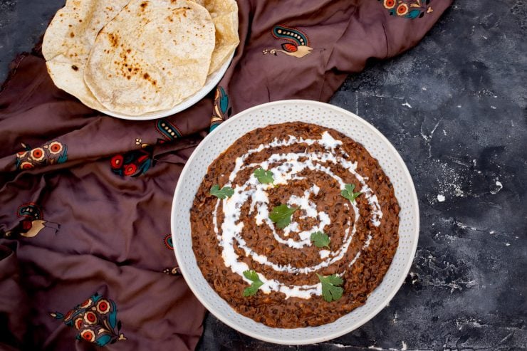 A bowl of Dal Makhani with roti, topped with cilantro