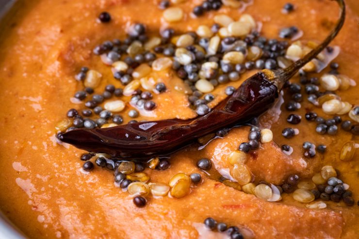 Close up of the vaghar on top of the tomato chutney