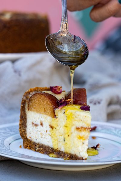 Gulab jamun syrup dripping from a spoon over a slice of cheesecake