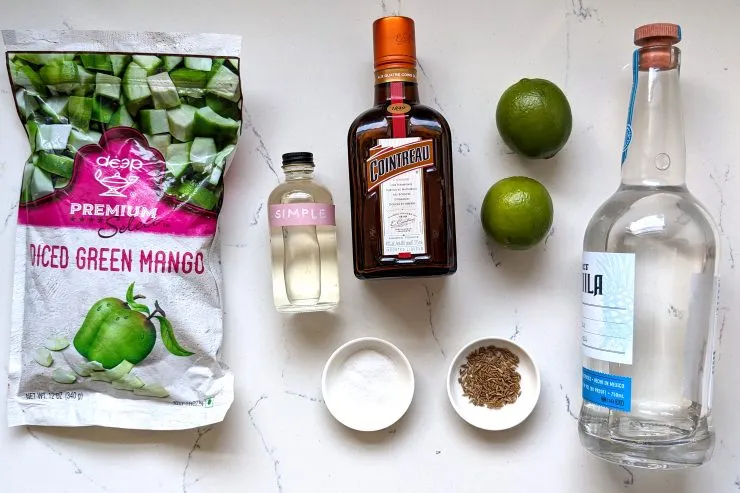 Ingredients for Raw Mango Margarita: frozen raw mango, simple syrup, Cointreau, tequila, limes, toasted cumin, salt