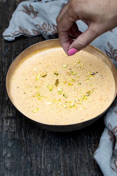 Garnishing the kheer with pistachio slivers