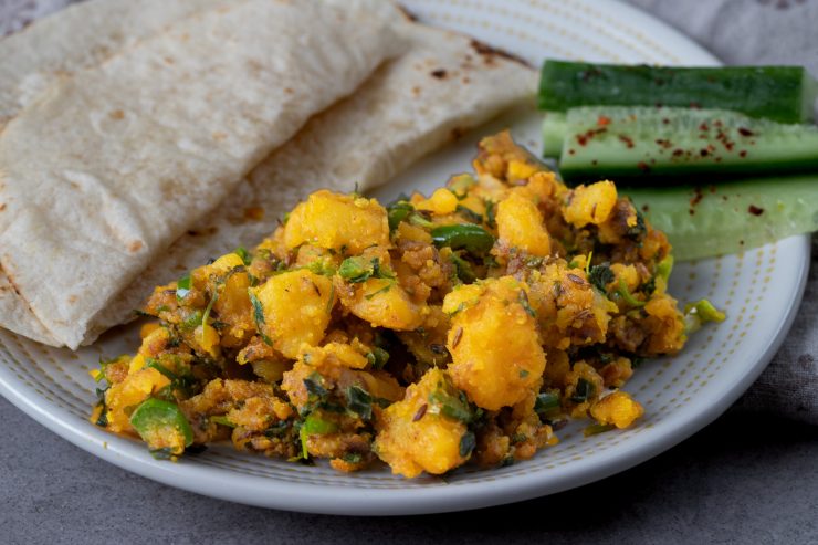 A plate of methi batata nu shaak served with roti and cucumber