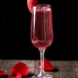 Rose mimosa garnished with a strawberry and decorated with rose petals.
