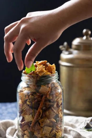 Placing a curry leaf on a jar of Chex chevdo