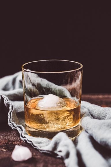 A glass of ghee washed whiskey with a craft cocktial ice ball.